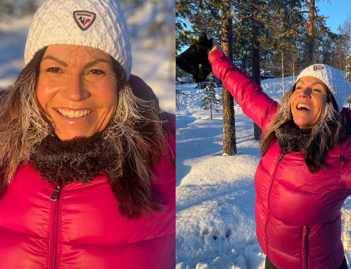 En glad Karin Lindblom i rosa vinterjacka i vinterskog.